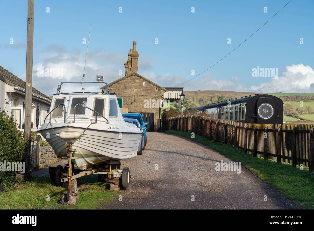 Blick auf die Küstensiedlung von West Bay, Dorset, Großbritannien - ein Boot im Vordergrund und The Station Kitchen - ein Restaurant in einem ehemaligen Eisenbahnwaggon. Stockfoto