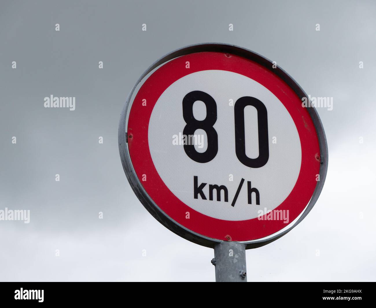 Rundes Schild, Geschwindigkeitsbegrenzung, wolkiger Himmel. Zeichen warnen vor einer Höchstgeschwindigkeit von 80 km h. Stockfoto
