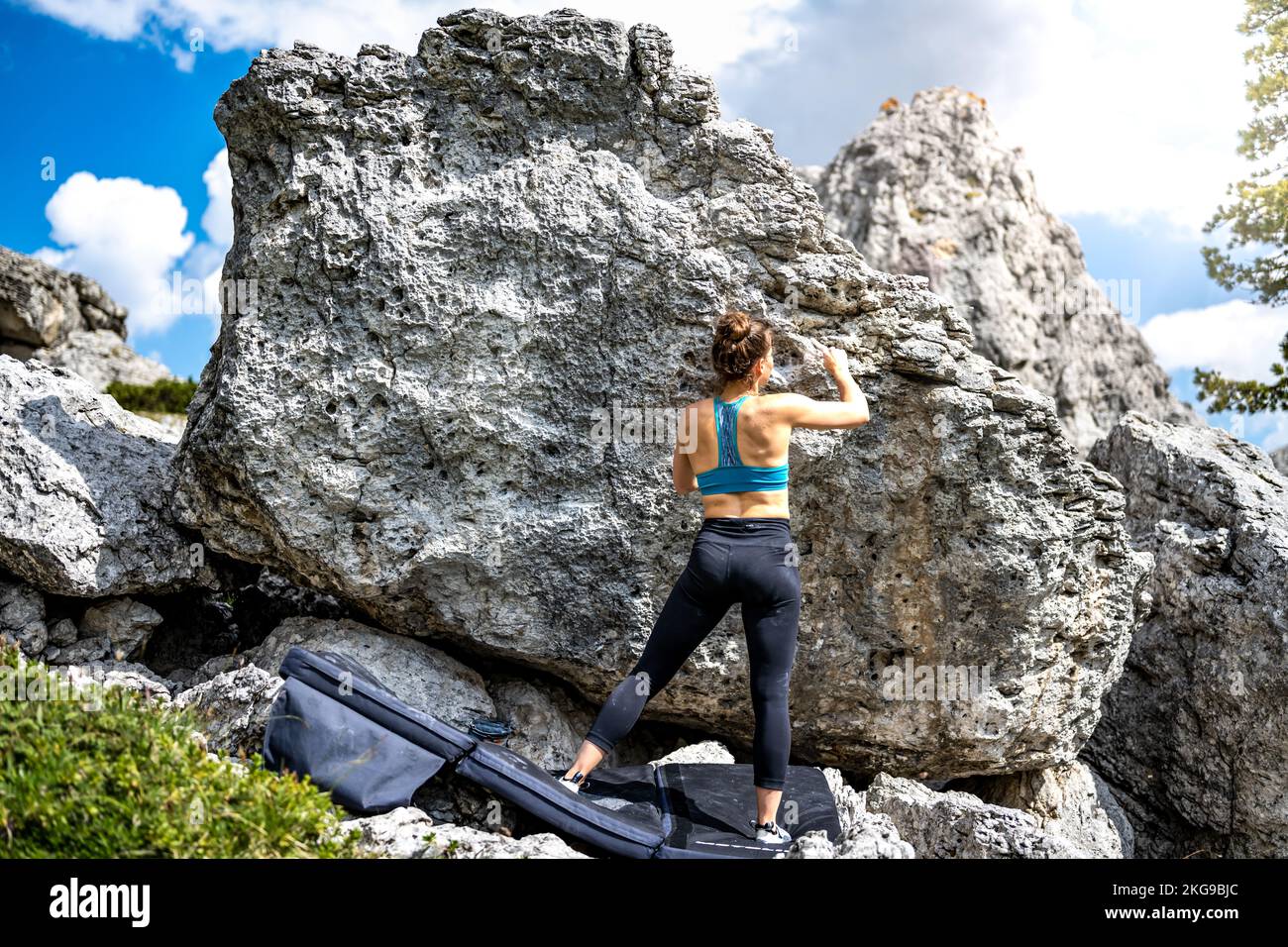 Beschreibung: Sportliche Frau klettert nachmittags auf einen Felsblock. Falzarego Pass, Dolomiten, Südtirol, Italien, Europa. Stockfoto