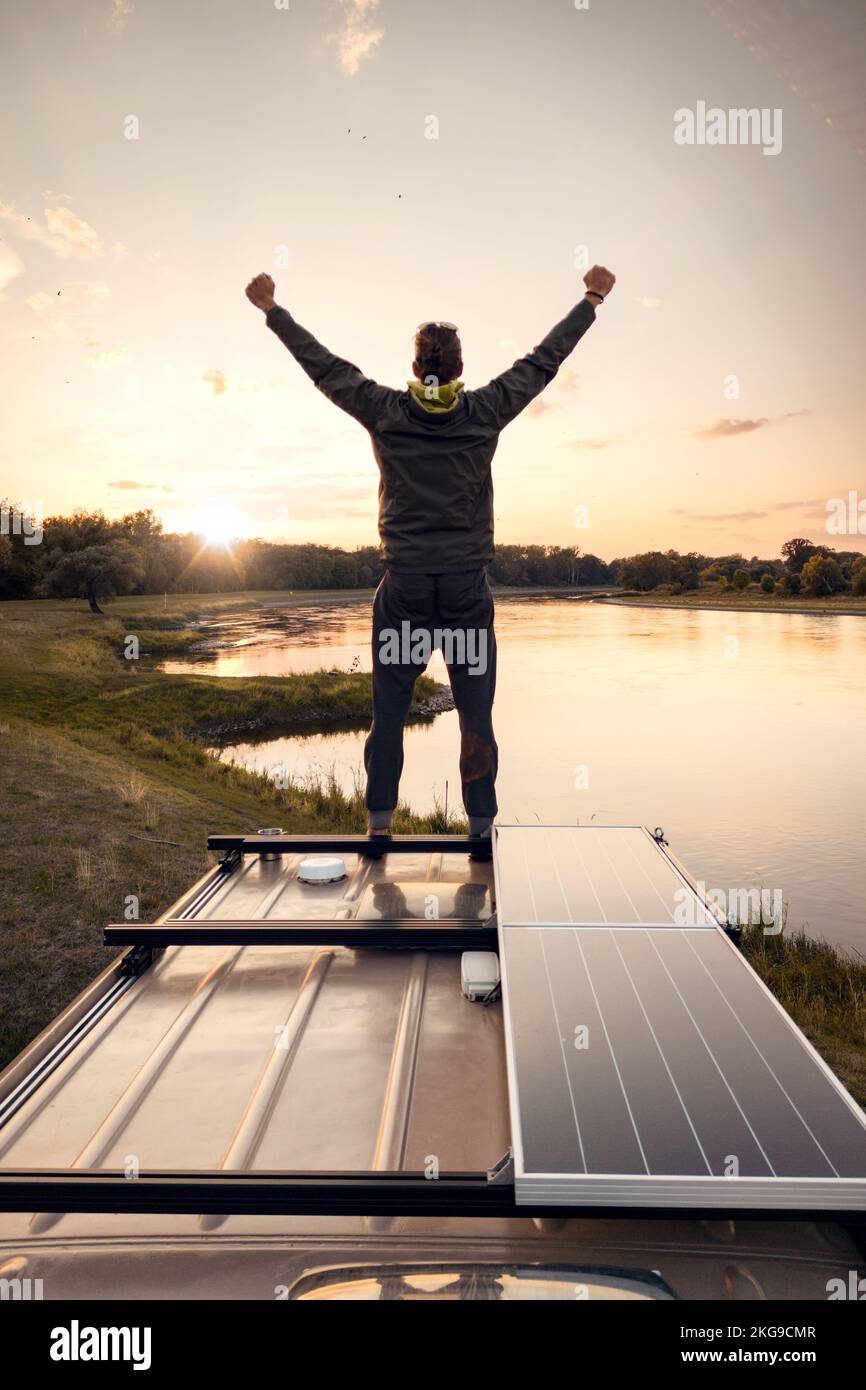 Ein Mann genießt seine Freiheit auf einem Wohnmobil bei Sonnenuntergang Stockfoto