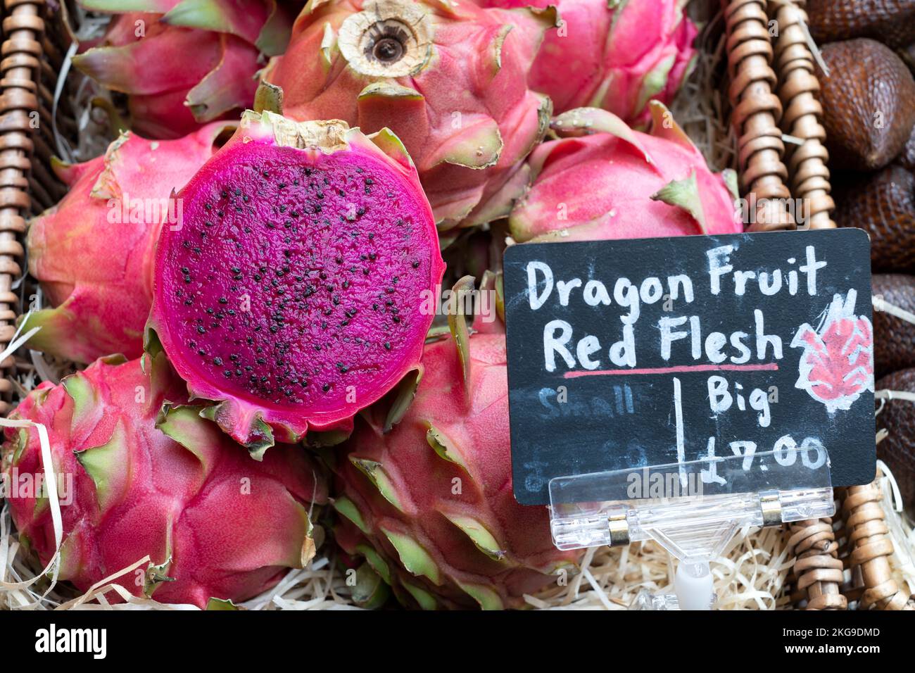 Rote Drachenfrucht Hylocereus costaricensis oder Pitahaya eine tropische Frucht. Die Früchte, eine in der Mitte, werden auf einem englischen Markt für frische Erzeugnisse verkauft Stockfoto