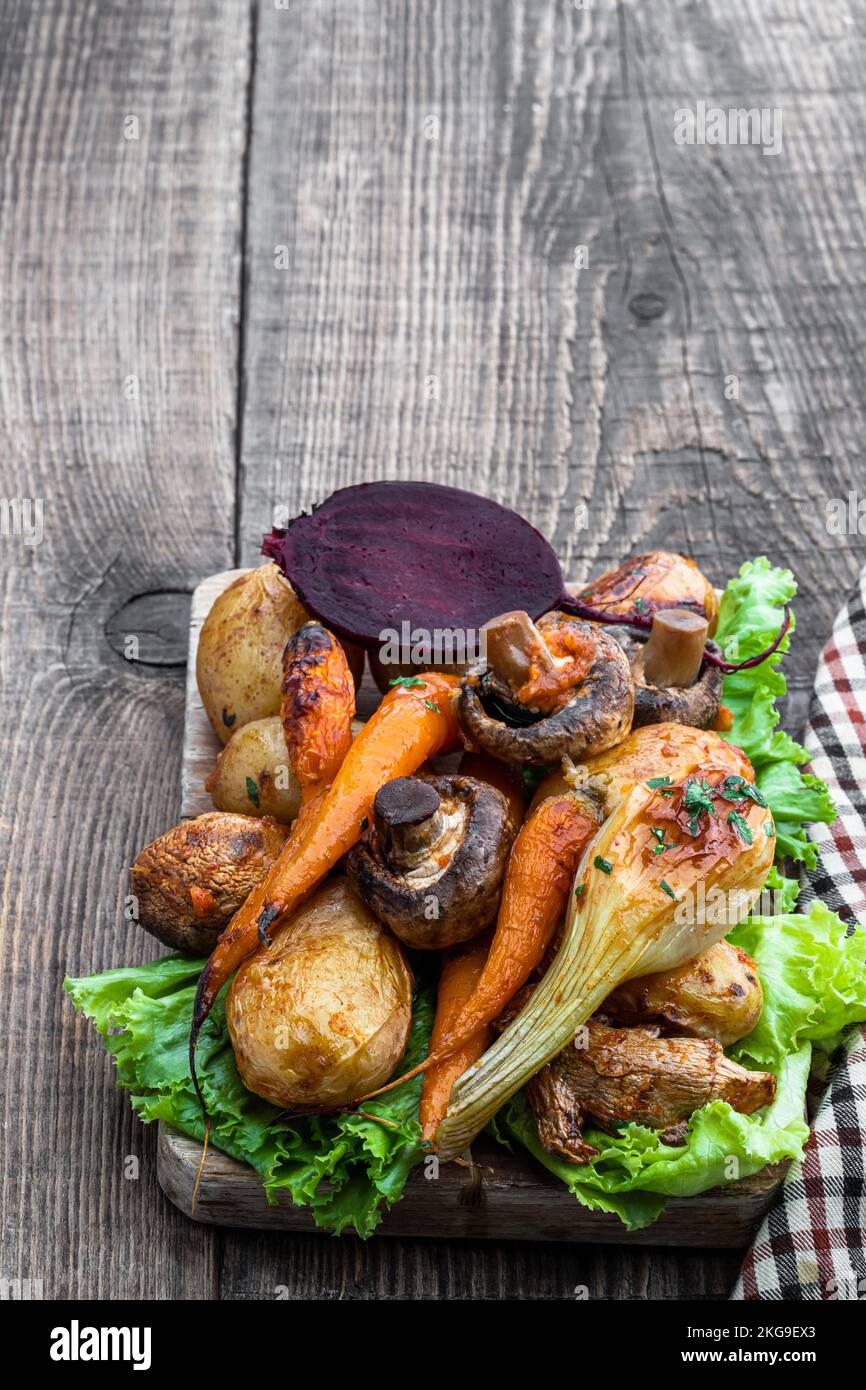 Im Ofen geröstetes Gemüse mit Gewürzen und Kräutern auf Holzbrett Stockfoto