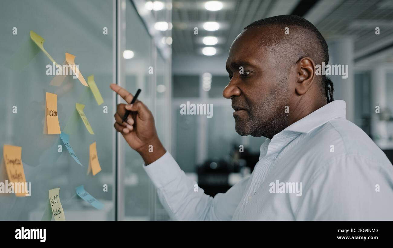 Afrikanischer Geschäftsführer Content Manager entwickeln Strategieplan verwalten Arbeitsaufgaben im Unternehmen lesen Haftnotizen an Bord schreiben Ideenprojekt Stockfoto