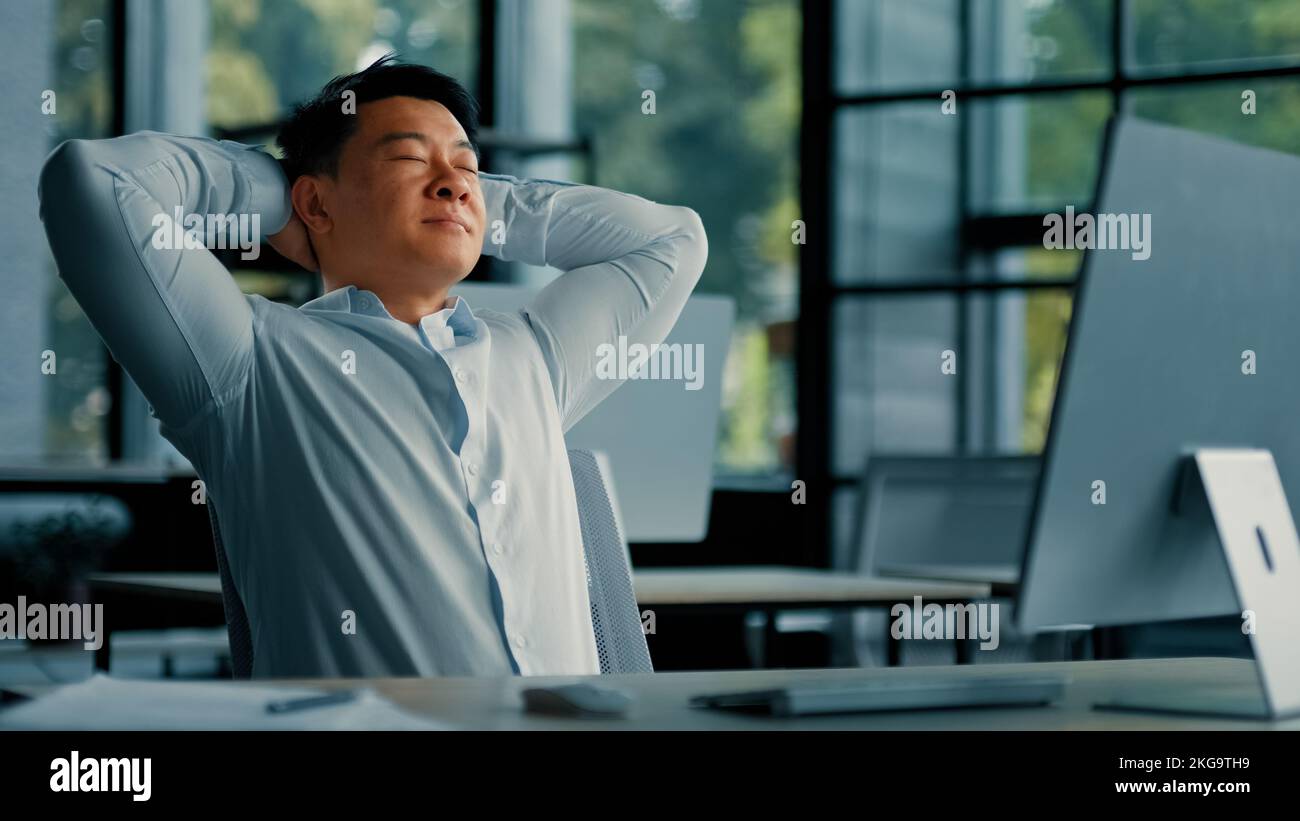 Asiatischer koreanischer Senior Geschäftsmann Mitarbeiter allein entspannen Lehnen Sie sich auf Bürostuhl Hände hinter den Kopf legen Komfort Ruhe fühlt sich Zufriedenheit durch Computerarbeit Stockfoto