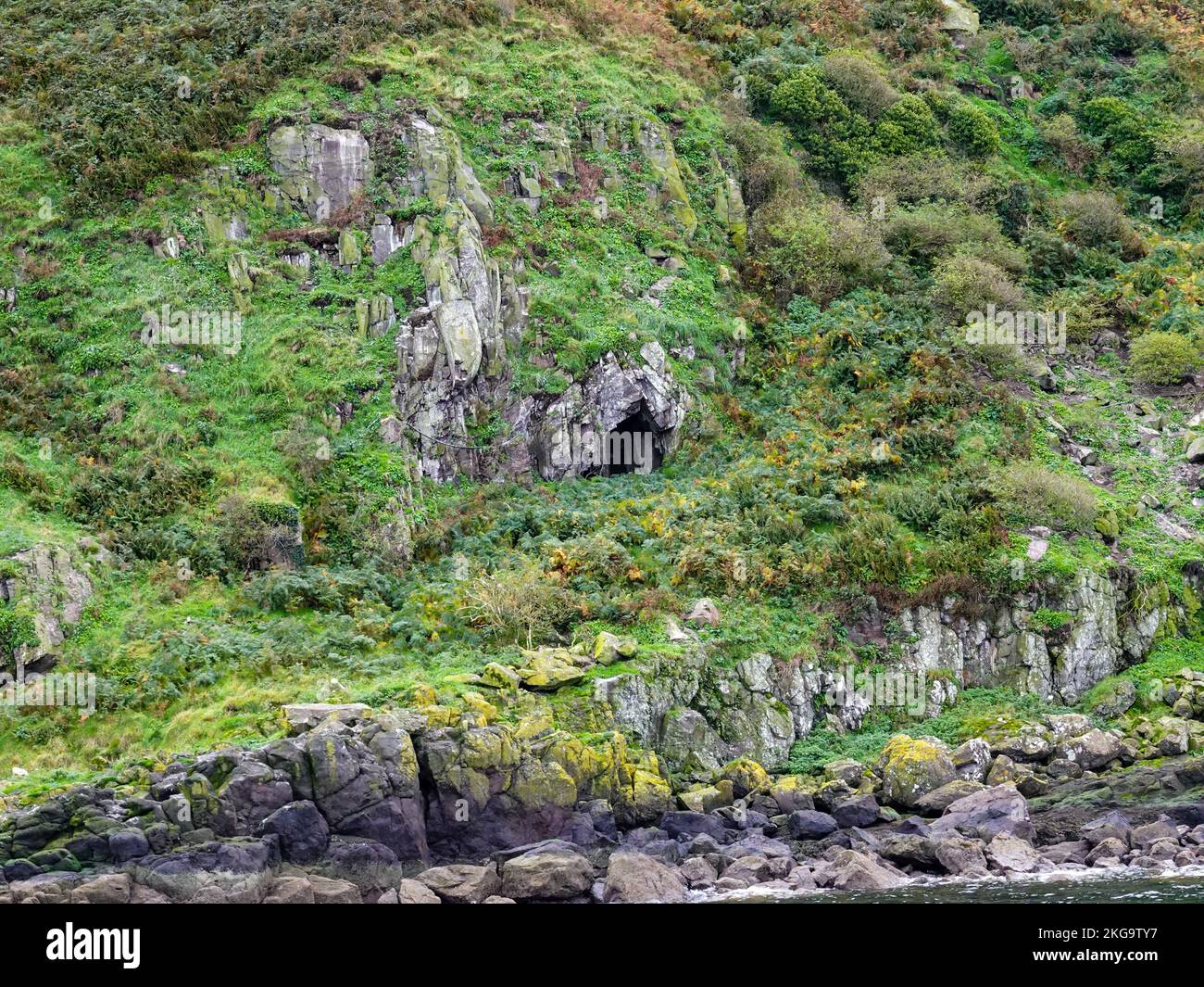 Höhlenöffnung auf der felsigen Seite der Insel Little Cumbrae im Firth of Clyde, Schottland, Großbritannien. Stockfoto
