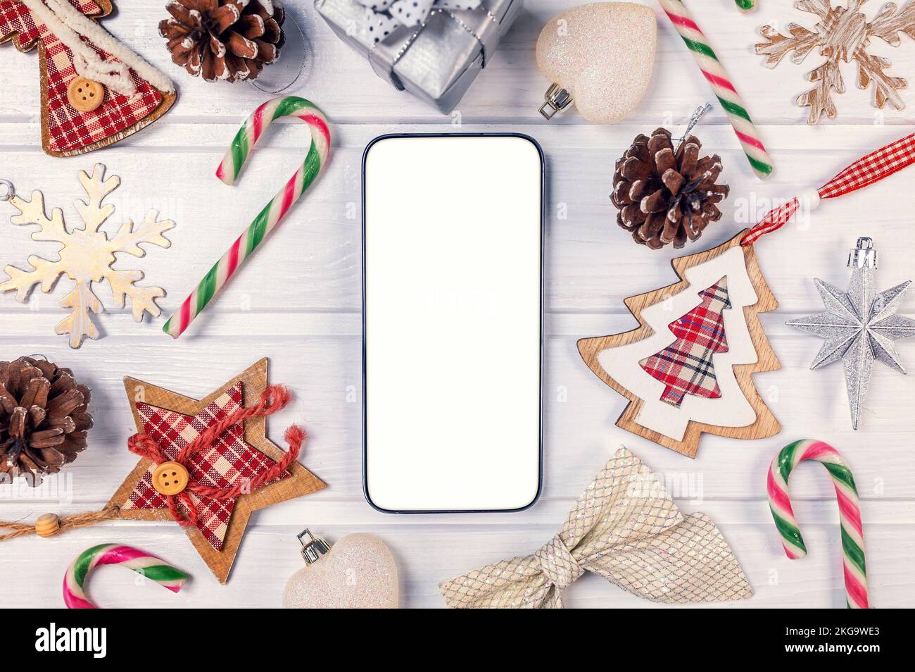Smartphone-Modell mit rustikalen Weihnachtsdekorationen auf dem Holztisch für die App-Präsentation. Blick von oben Stockfoto