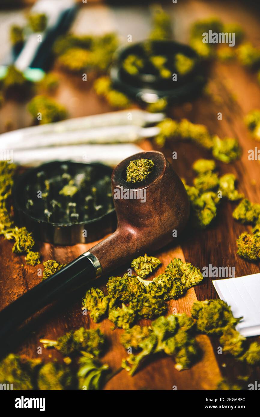 Marihuana-Drogen auf einem Holztisch. Rauchpfeife, Mahlwerk und cbd sativa oder indica tgk-Knospen. Papier für Gelenke Stockfoto