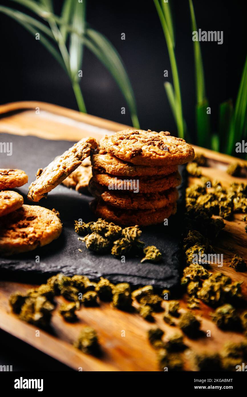 Marihuana-Kekse, Drogen in Lebensmitteln, thc und cbd-Brownies. Drogen und Marihuana-Knospen auf einer Planke vor dem Hintergrund des Wachstums Stockfoto