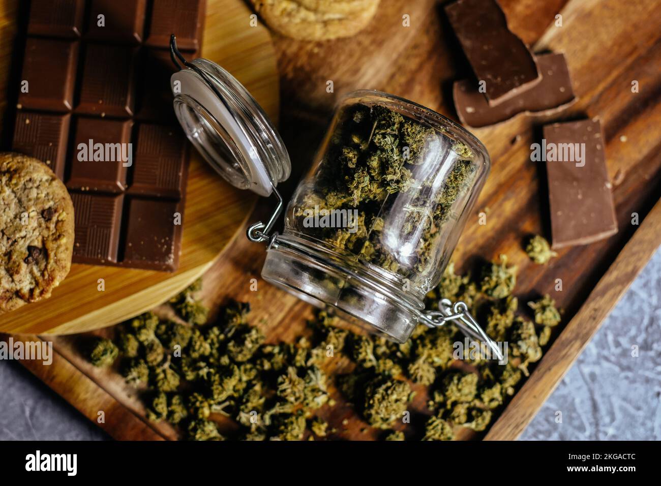 Schokolade und Kekse mit Marihuana auf dem Hintergrund eines Holztisches und Marihuana-Zapfen. CBD und THC, Sativa und Indica. Marihuana-Gras im Futter Stockfoto