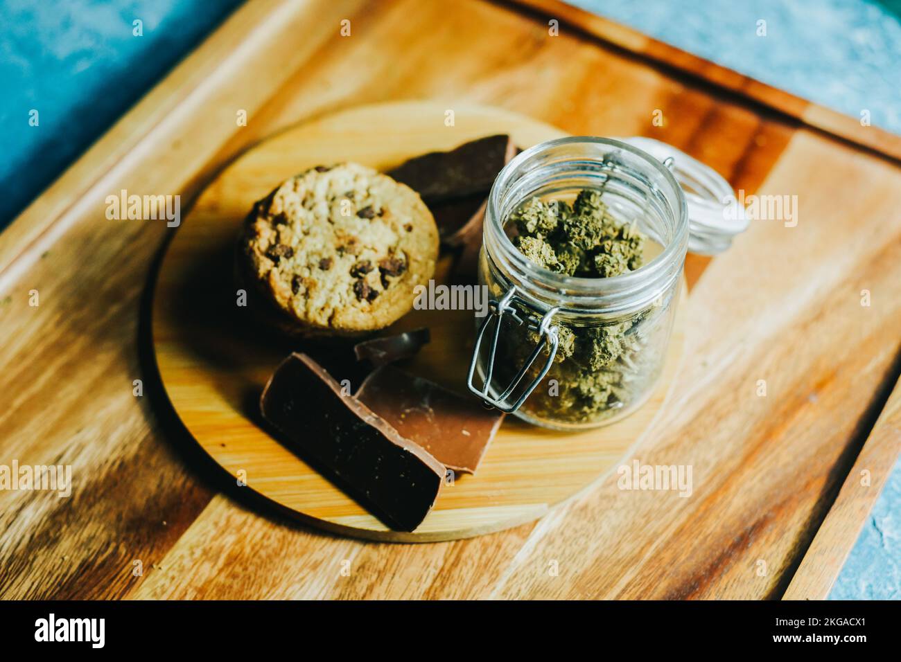 Schokolade und Kekse mit Marihuana auf dem Hintergrund eines Holztisches und Marihuana-Zapfen. CBD und THC, Sativa und Indica. Marihuana-Gras im Futter Stockfoto