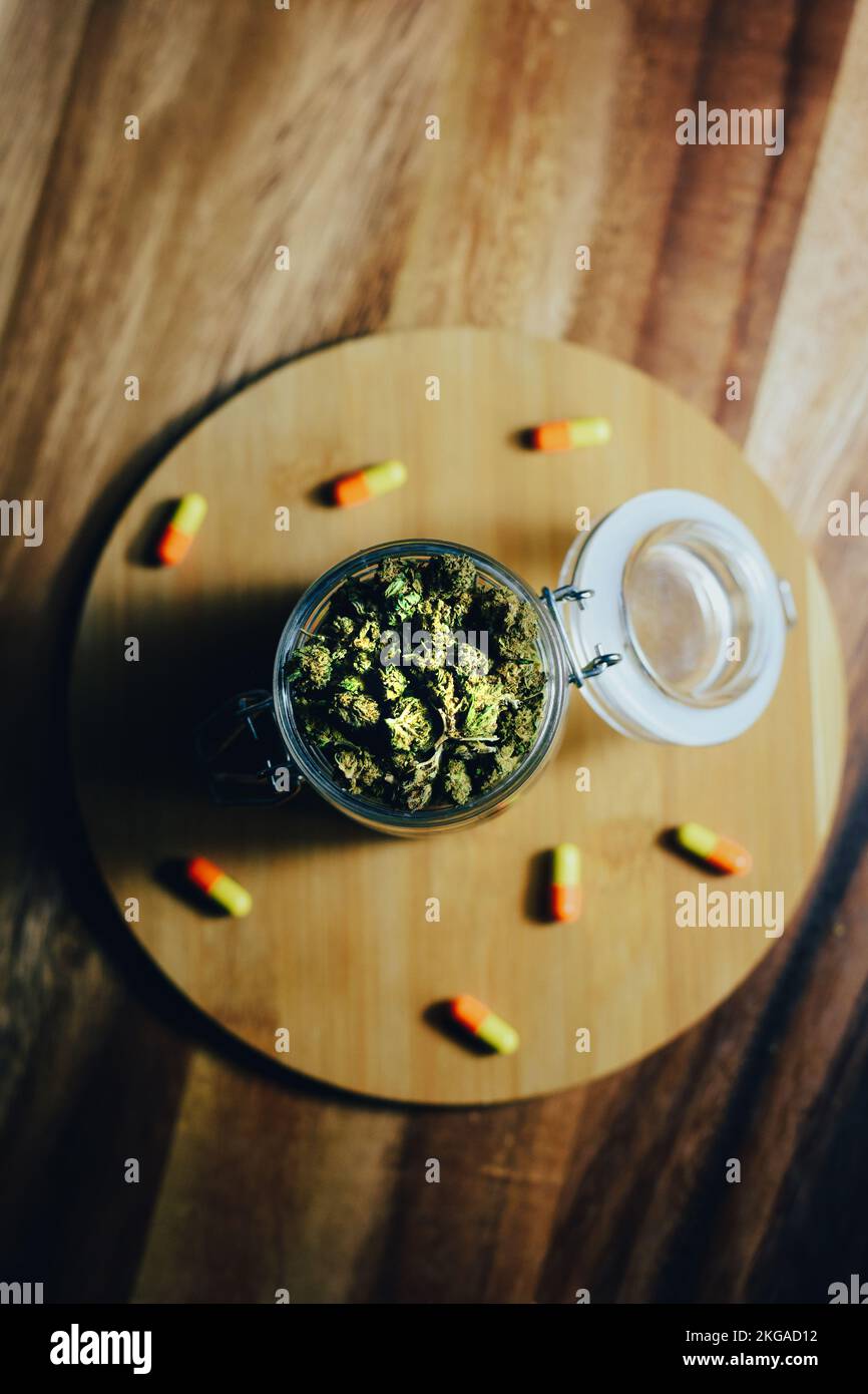 Marihuana in Medizin und Behandlung. Marihuana-Knospen und Pillen in einem Glasgefäß Stockfoto