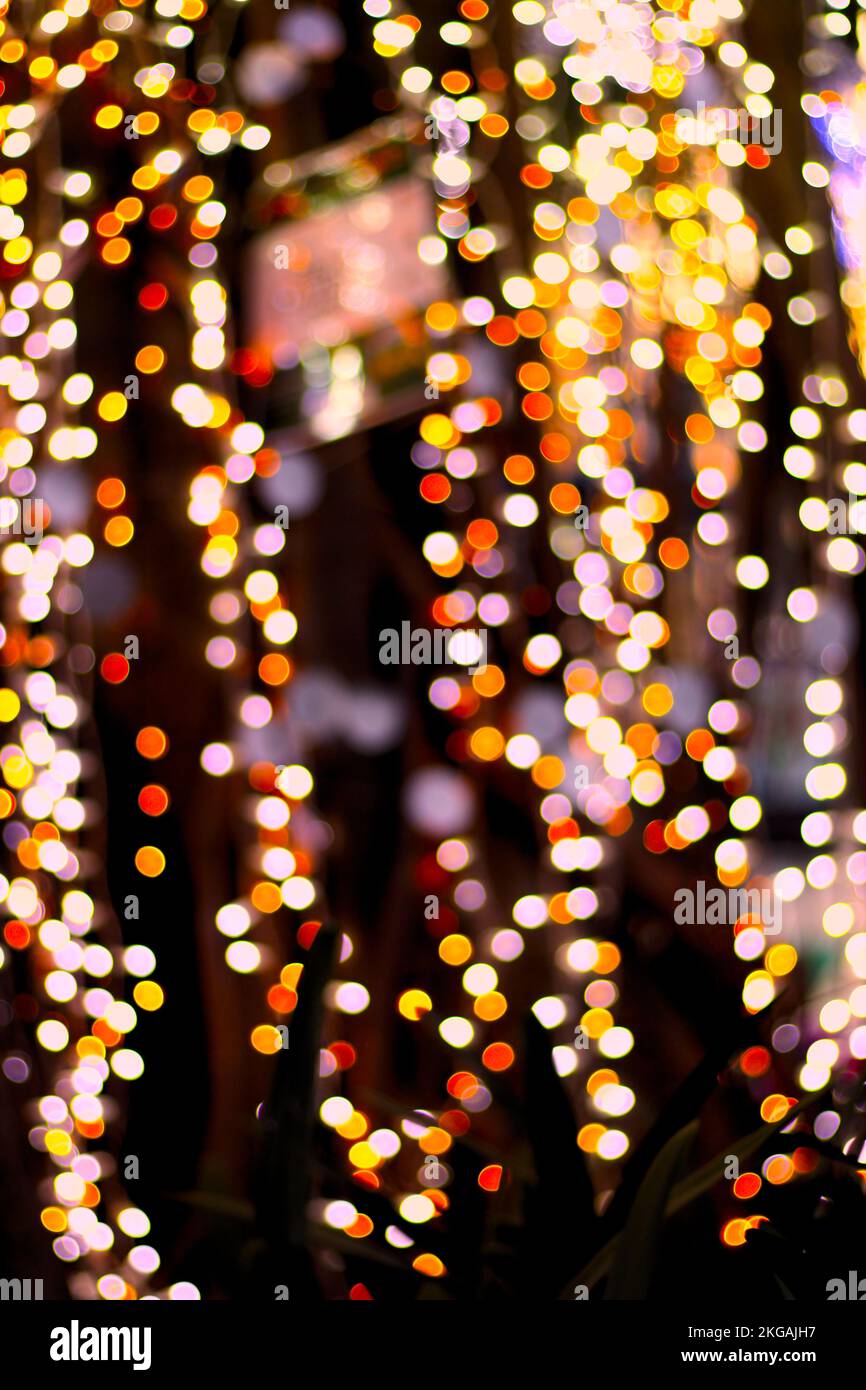 Vertikales Bild von farbigen Lichtern mit Bokeh-Effekt auf dunklem Hintergrund für Feierlichkeiten, Weihnachten oder Neujahr Stockfoto