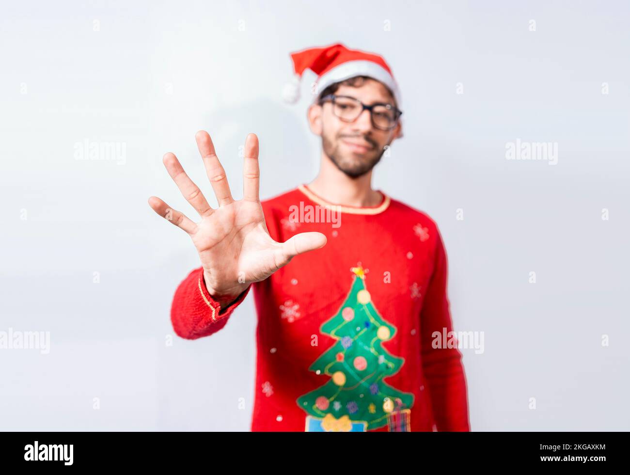 Ein Mann mit weihnachtsmütze, der mit den Fingern Nummer fünf zählt. Ein Mann im weihnachtskostüm, der mit den Fingern Nummer fünf zählt. Der Begriff des Menschen im weihnachtskostüm Stockfoto