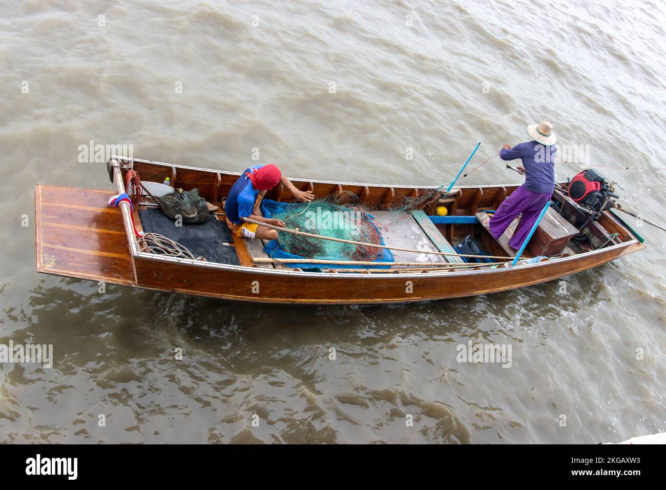 Asiatische Fischer segeln auf einem Boot und werfen ihre Netze ins Wasser Stockfoto