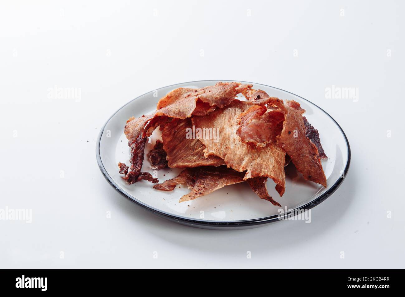 Gepökeltes Fleisch mit Gewürzen auf weißem Schneidebrett, weißer Hintergrund. Stockfoto
