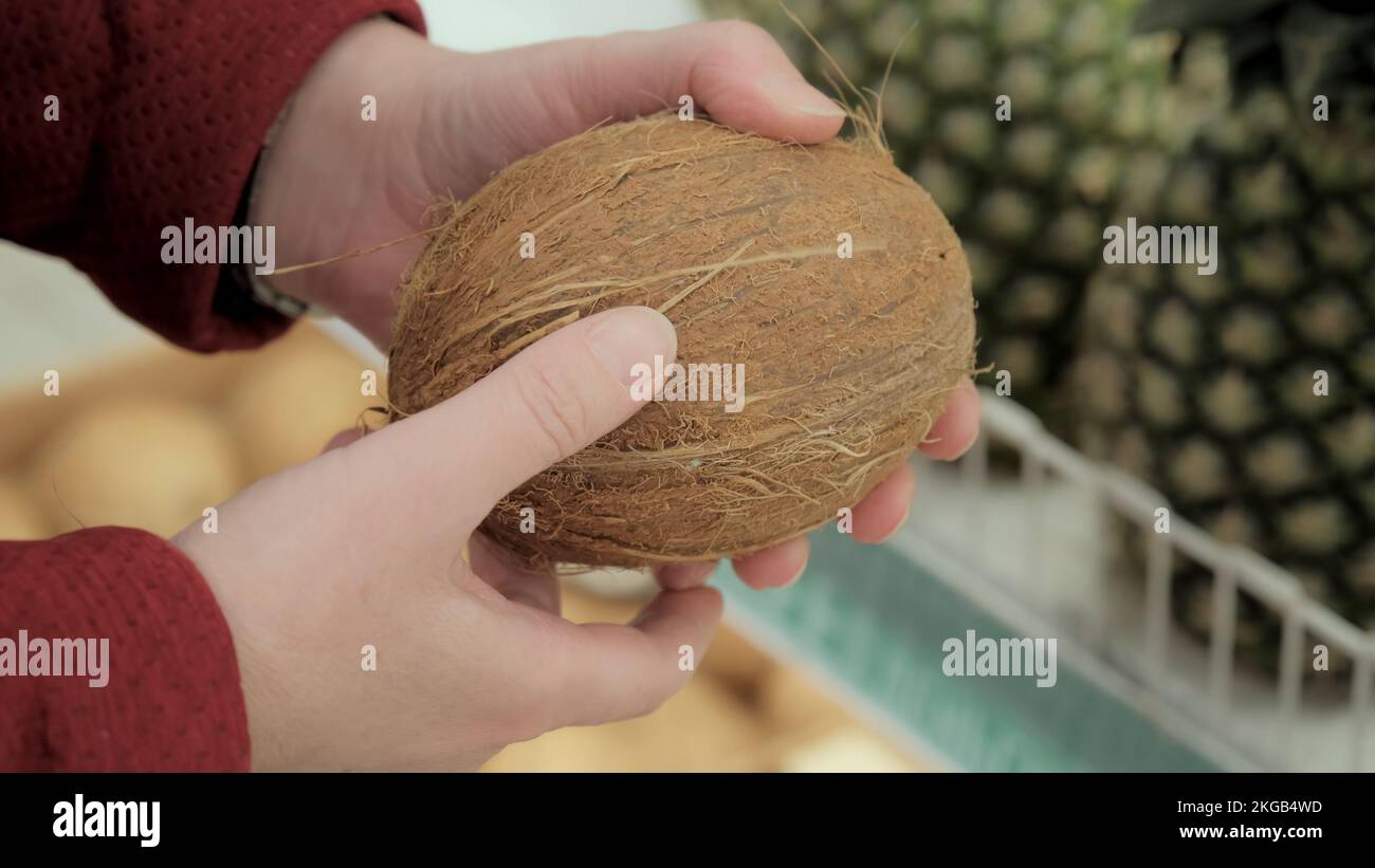 Das Mädchen sucht sich eine Kokosnuss im Supermarkt aus. Nahaufnahme Stockfoto