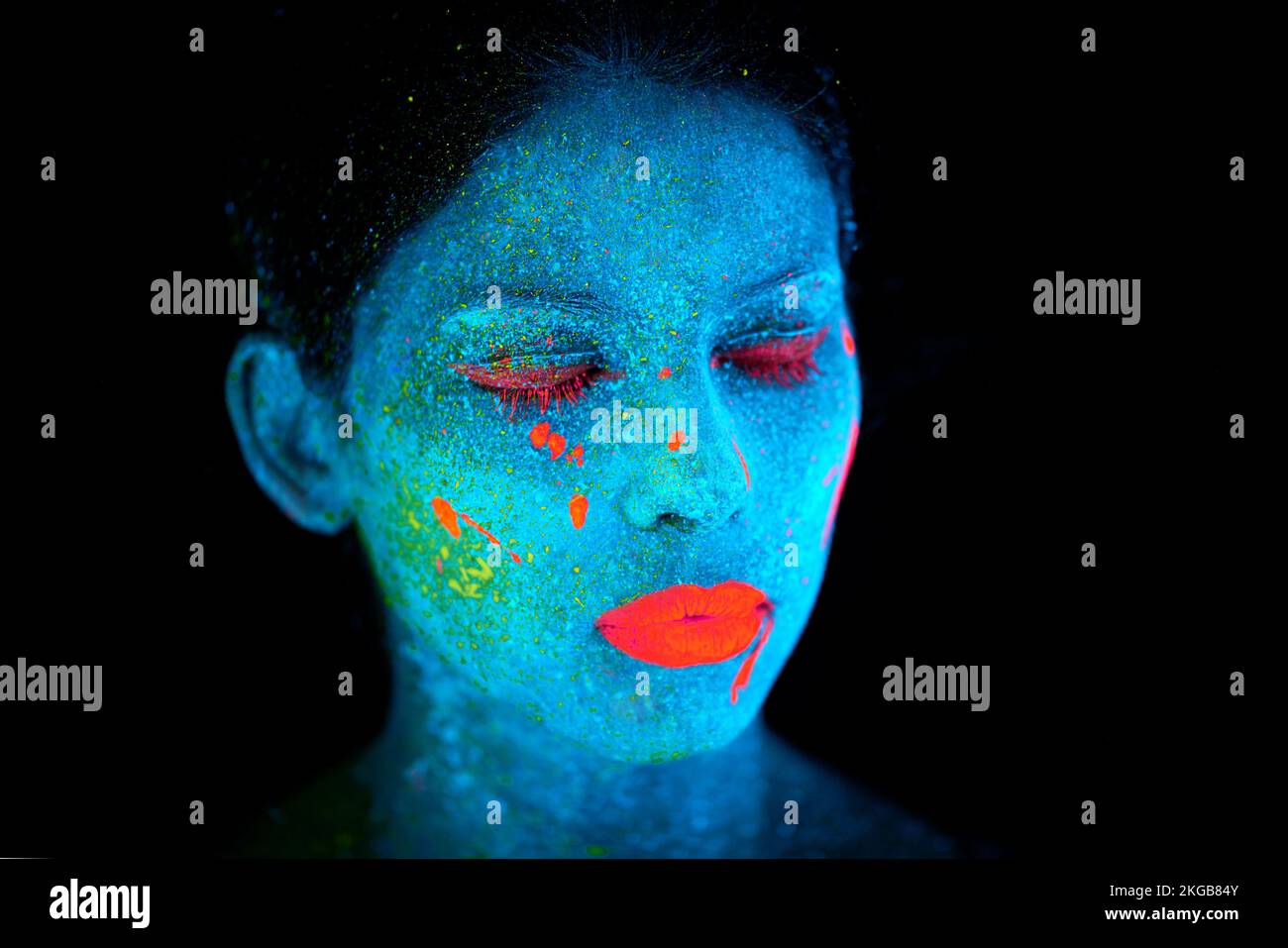 Schönheit nicht aus dieser Welt. Eine junge Frau, die mit Neonfarbe im Gesicht posiert. Stockfoto
