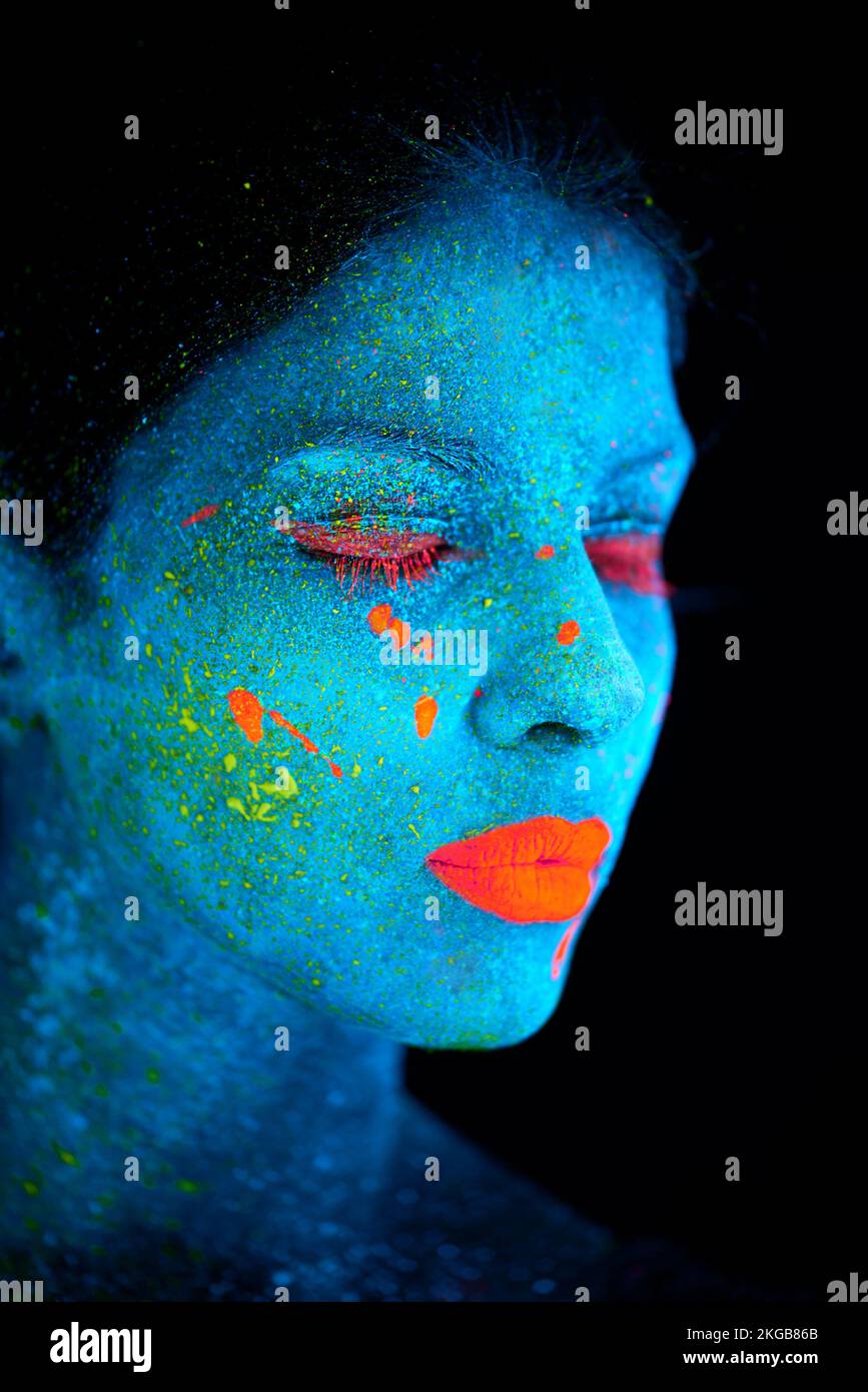 Fantastische Schönheit. Eine junge Frau, die mit Neonfarbe im Gesicht posiert. Stockfoto