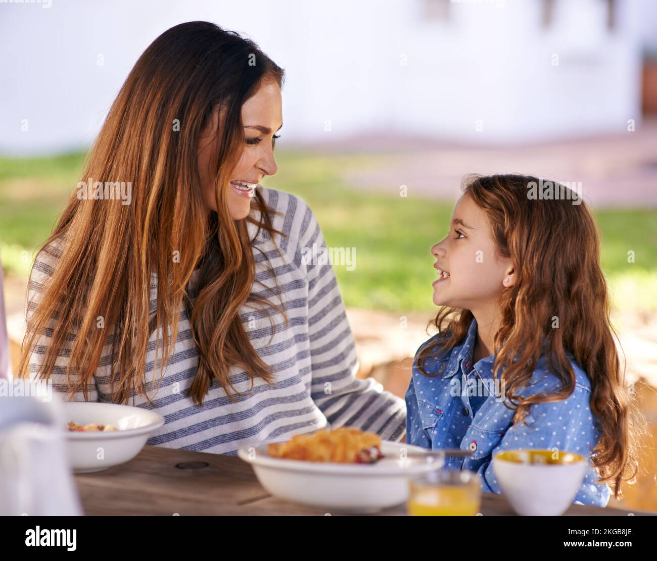 Das Frühstück lacht. Eine Mutter und Tochter, die draußen zusammen frühstücken. Stockfoto