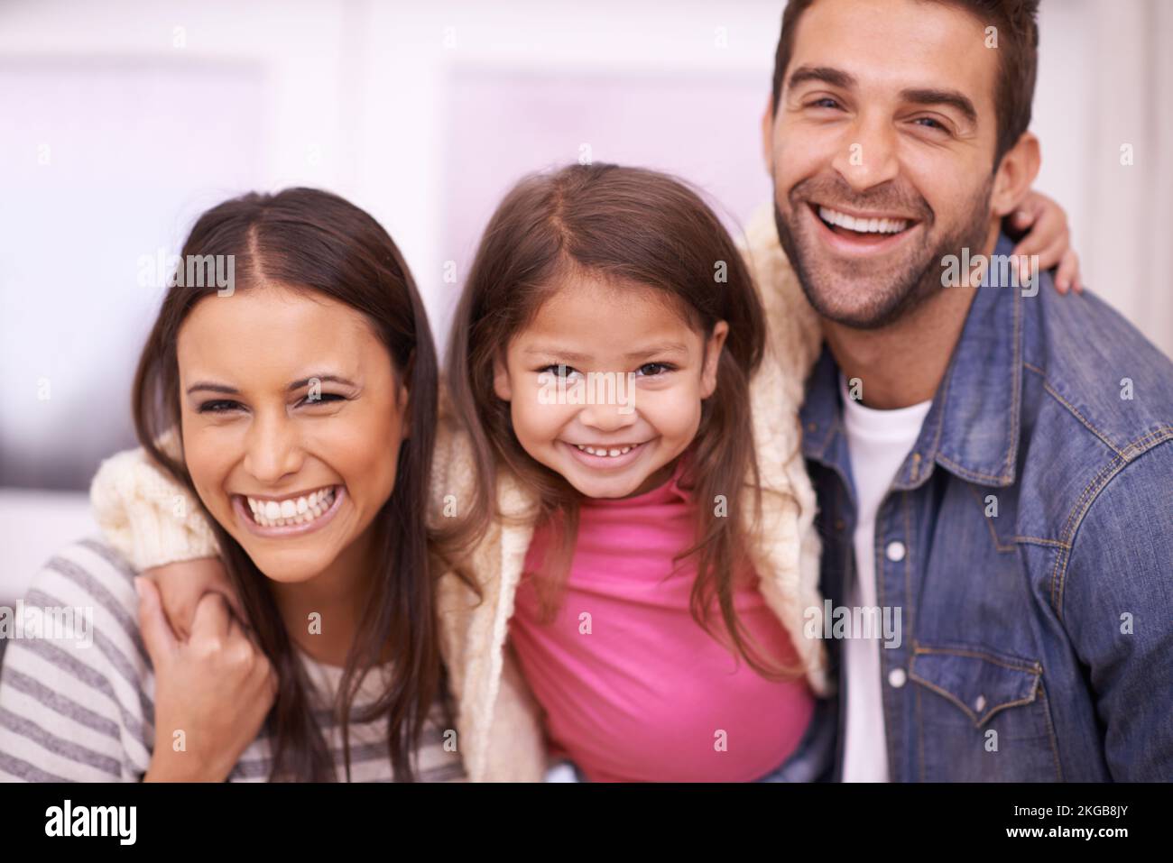 Glückliche Momente zusammen. Porträt einer glücklichen, jungen Familie, die zu Hause zusammensitzt. Stockfoto