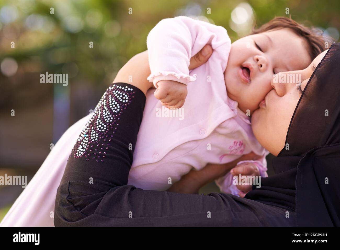 Hier ist ein dicker Kuss von Mami. Eine muslimische Mutter und ihr kleines Mädchen. Stockfoto
