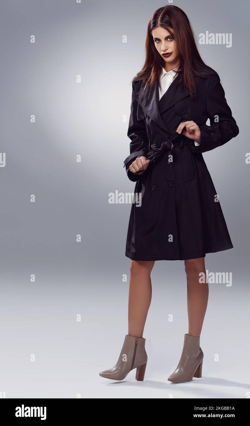 Flirtende Fashionista. Studioaufnahme einer stilvoll gekleideten jungen Frau vor grauem Hintergrund. Stockfoto