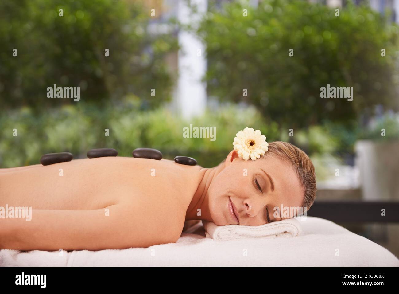 Die Hot-Stone-Therapie lässt mich schlafen. Eine Frau in einem Day Spa, die sich auf einem Massagetisch entspannt. Stockfoto