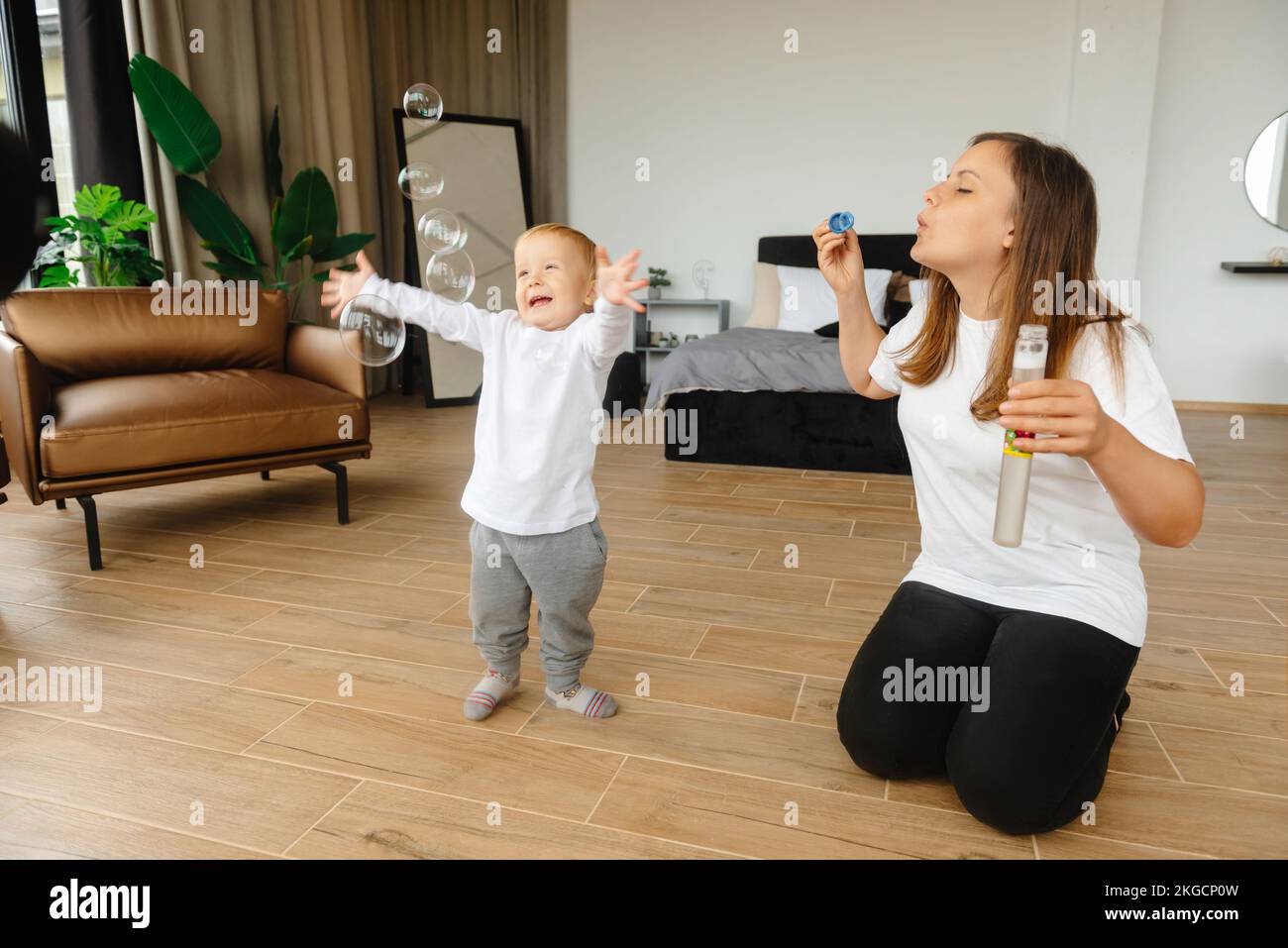 Mutter und Sohn spielen mit Seifenblasen. Das Kind genießt die Seifenblasen. Die Familie sitzt zu Hause und spielt mit Seifenblasen Stockfoto