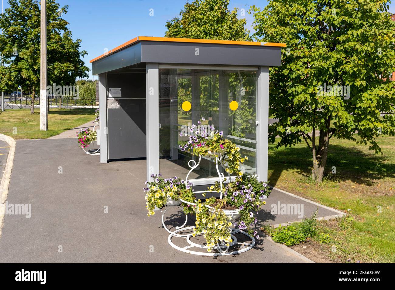 Eine leere Bushaltestelle mit wunderschönen Blumen in Töpfen und Vasen Stockfoto