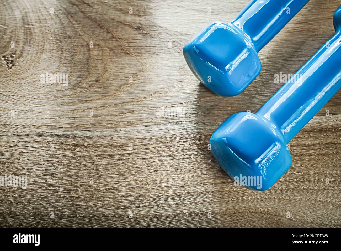 Blaue Kurzhantel-Gewichte auf Holzbrett-Fitnesskonzept. Stockfoto