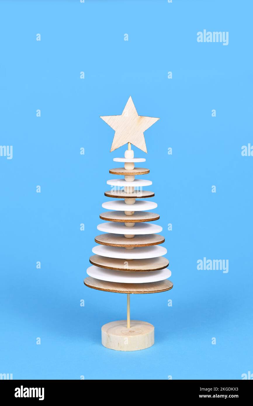 Hölzerne Weihnachtsbaumdekoration aus runden Holzplatten auf blauem Hintergrund Stockfoto
