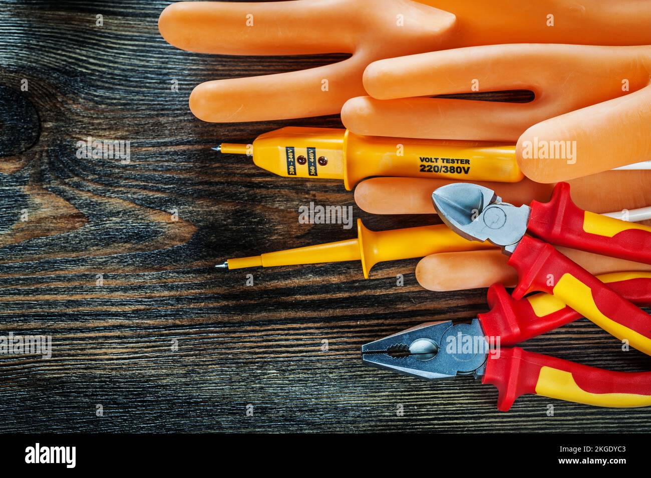 Dielektrische Handschuhe Elektrotester isolierte Schneidzange auf Holzplatte. Stockfoto