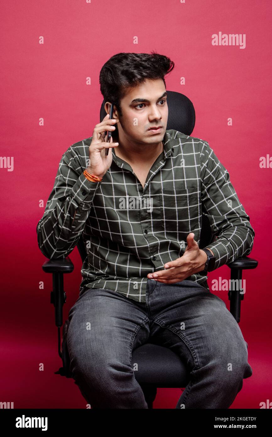 Gestresster und frustrierter, streitender Boss über das Handy im Studio-Hintergrund. Wütende Männer, die auf ihrem Smartphone diskutieren oder Probleme lösen. Stockfoto