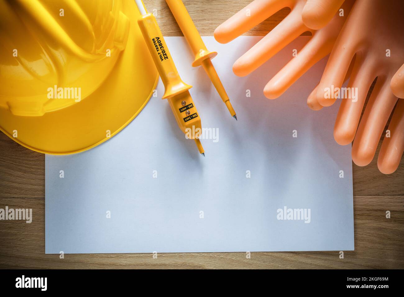 Blatt dielektrischer Schutzhandschuhe Bauhelm elektrischer Tester auf Holzbrett. Stockfoto