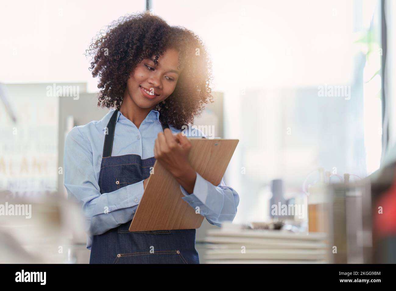 Junge weibliche Managerin im Restaurant mit Notizbuch. Ladenbesitzerin mit offenem Schild. Konzept für kleine Unternehmen Stockfoto