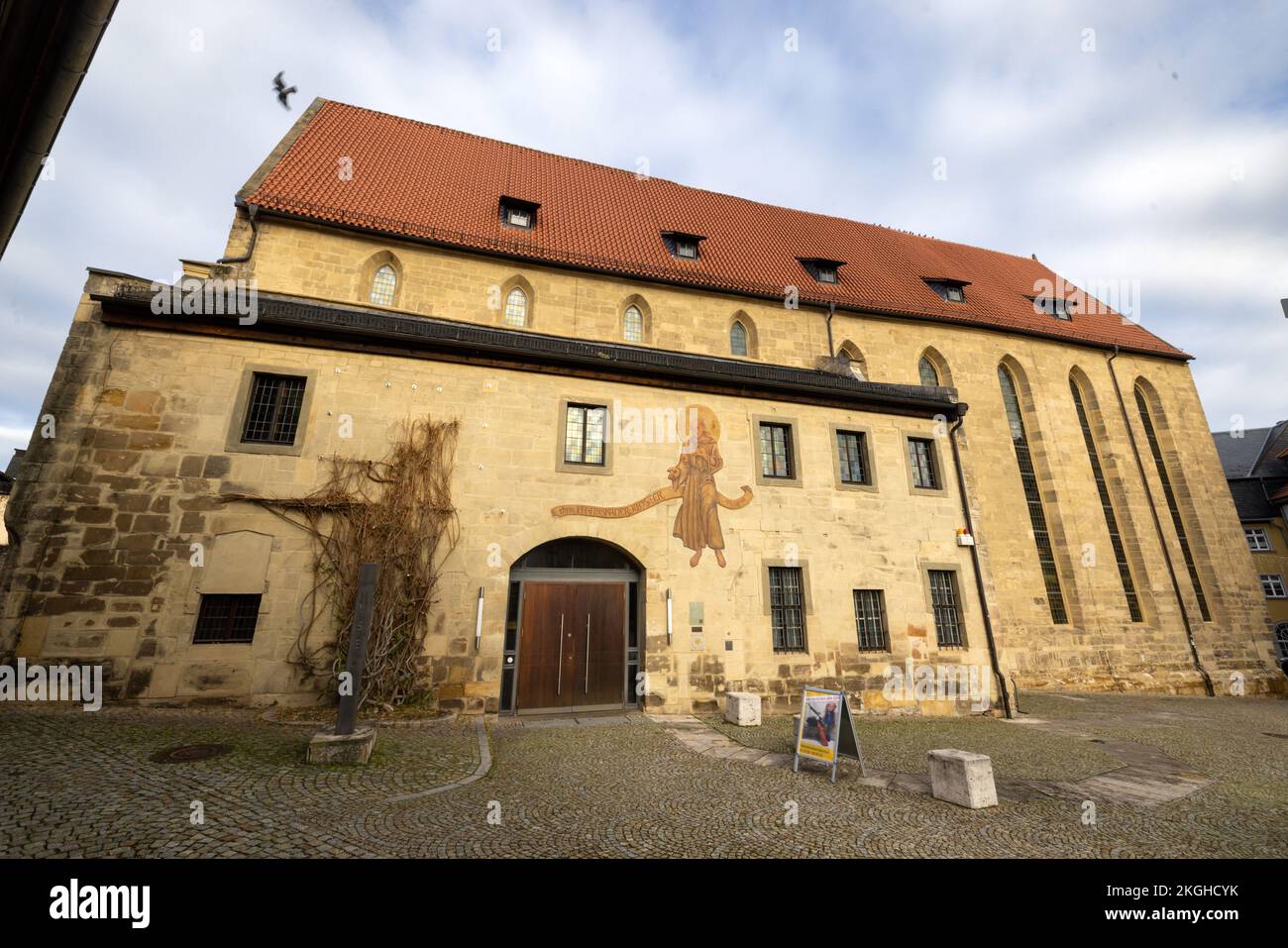 Saalfeld, Deutschland. 23.. November 2022. Ein Franziskanermönch ist über dem Eingang zum Stadtmuseum gemalt. Im Kloster ist ab heute ein Dreifachfenster mit gotischen spitzen Bögen aus dem Jahr 1250 zu sehen. Der älteste erhaltene Teil des ehemaligen Franziskanerklosters wurde im Oktober 2022 wieder entdeckt, nachdem er seit einer Wiederaufbauphase um 1480 abgeriegelt wurde. Kredit: Michael Reichel/dpa/Alamy Live News Stockfoto