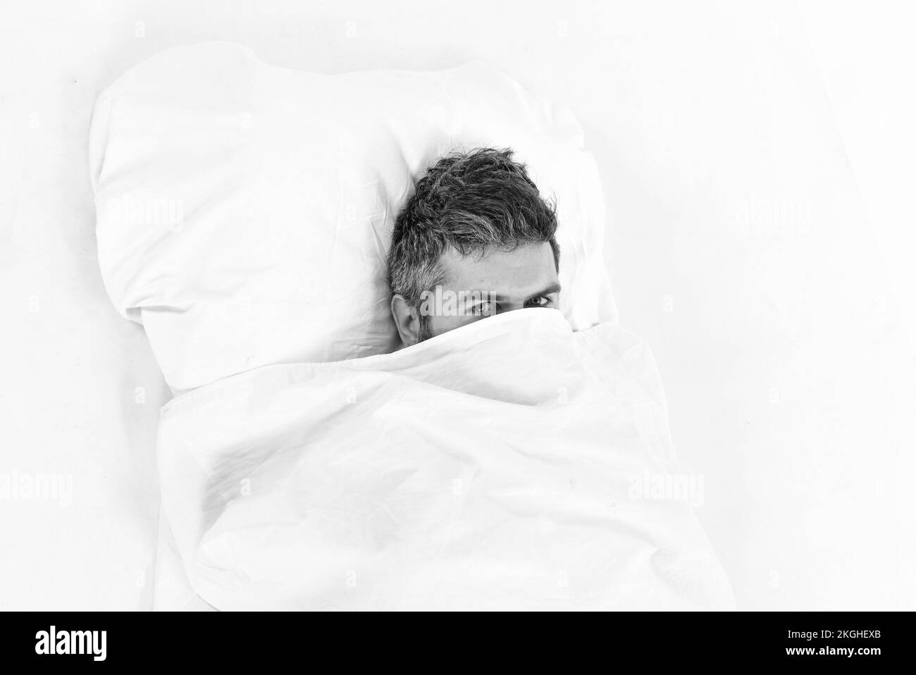 Der Kerl versteckt sein Gesicht unter der Decke. Faul und faul Stockfoto