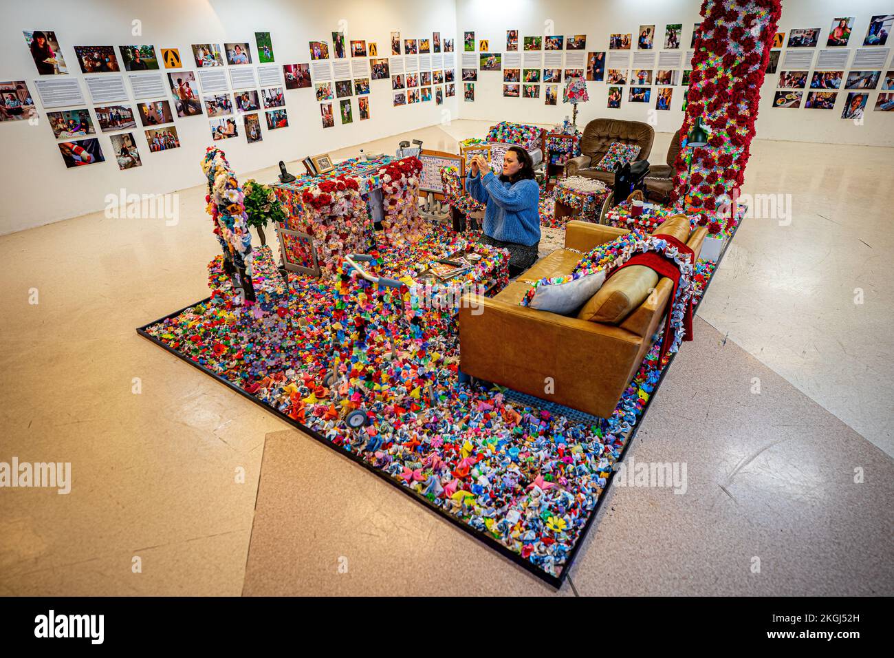 Eine Installation von Blumen von Carina Andrews (im Bild) anlässlich des Carers Rights Day am 24. November im Einkaufszentrum Galleries in Broadmead, Bristol. Das Stück besteht aus 40.138 Papierblumen, von denen jede eine unbezahlte Pflegekraft in der Gegend von Bristol repräsentiert. Die Blumen werden 2022 von Pflegekräften und Freiwilligen hergestellt und decken ein Modell des Wohnzimmers von Carinas Eltern ab. Bilddatum: Mittwoch, 23. November 2022. Stockfoto