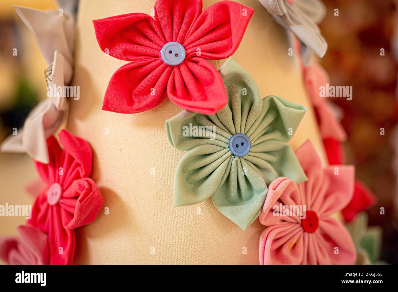 Nahaufnahme einer Blume aus Knöpfen und Material, die Teil einer Blumeninstallation ist, die von Carina Andrews anlässlich des Carers Rights Day am 24. November im Galleries Shopping Centre in Broadmead, Bristol, entworfen wurde. Das Stück besteht aus 40.138 Papierblumen, von denen jede eine unbezahlte Pflegekraft in der Gegend von Bristol repräsentiert. Die Blumen werden 2022 von Pflegekräften und Freiwilligen hergestellt und decken ein Modell des Wohnzimmers von Carinas Eltern ab. Bilddatum: Mittwoch, 23. November 2022. Stockfoto