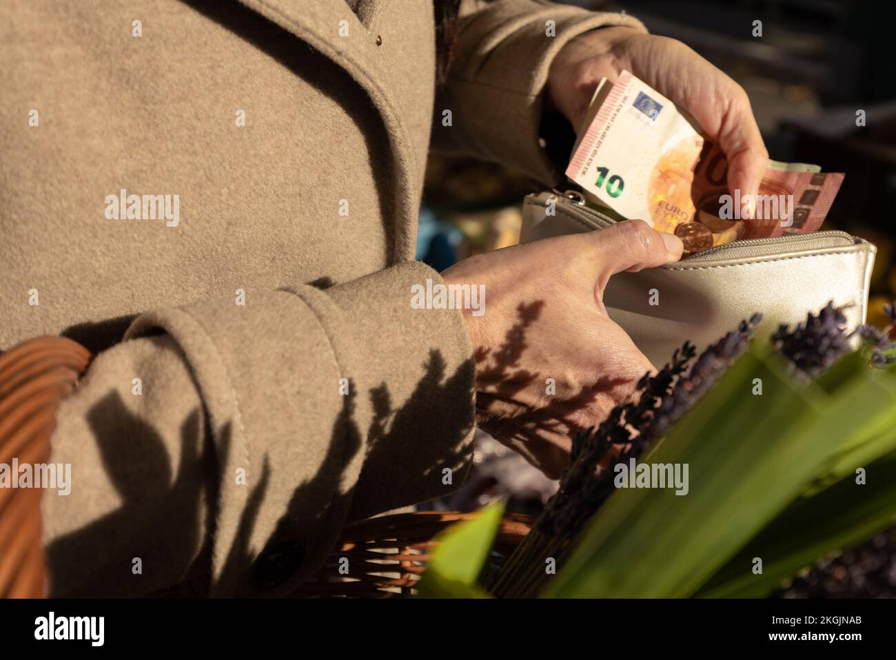 Eine Frau öffnete ihr Portemonnaie und zahlte für Einkäufe in einem offenen Lebensmittelmarkt in Österreich, Salzburg Stockfoto