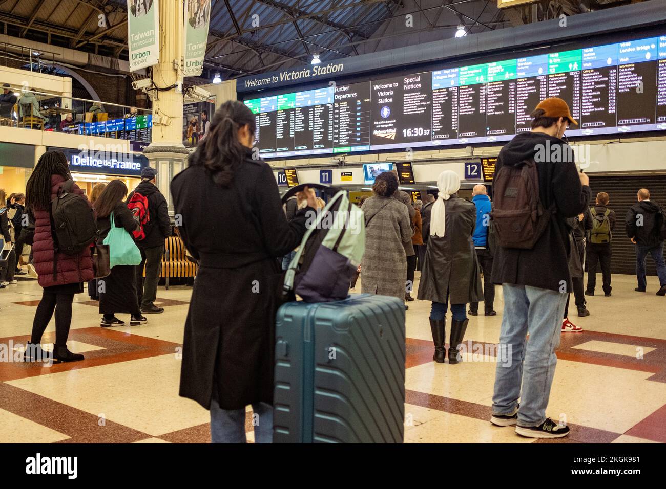 London - Dezember 2022: Passagiere, die auf Zuginformationen in der Haupthalle der Victoria Station in Westminster warten. Stockfoto