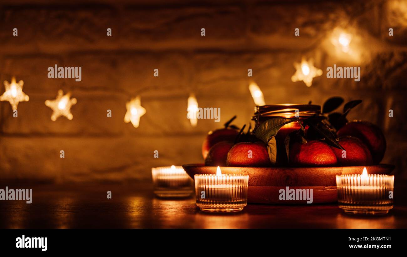 Weihnachten Kerzen Nacht Abend dunkler Hintergrund Webbanner. Zitruskerze für die Feiertage und saftige Orangen auf dem Küchentisch aus Holz. Neues Zuhause Stockfoto