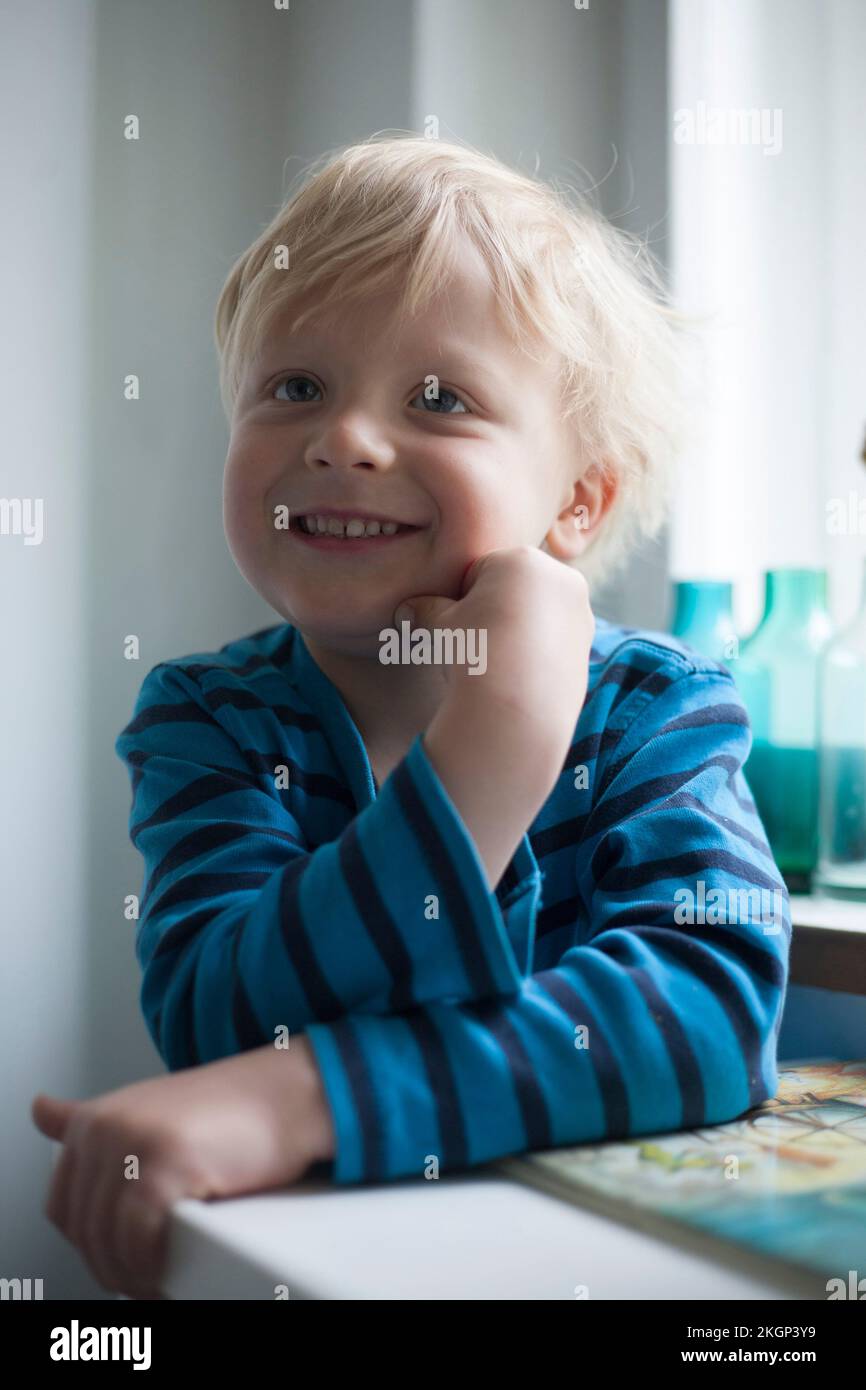 Porträt von lächelnden kleinen Jungen mit der Hand auf seinem Gesicht Stockfoto
