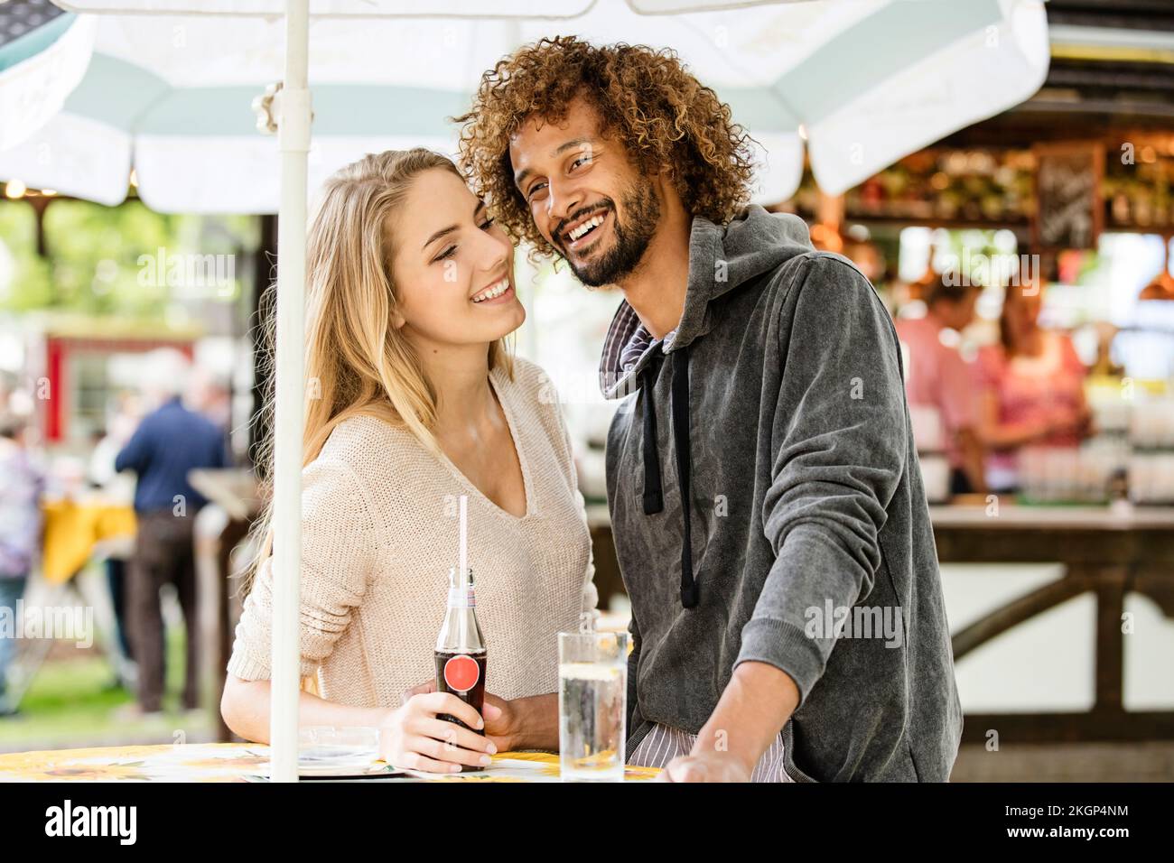 Ein junges Paar trinkt an einem lustigen, fairen Imbissstand ein Getränk Stockfoto
