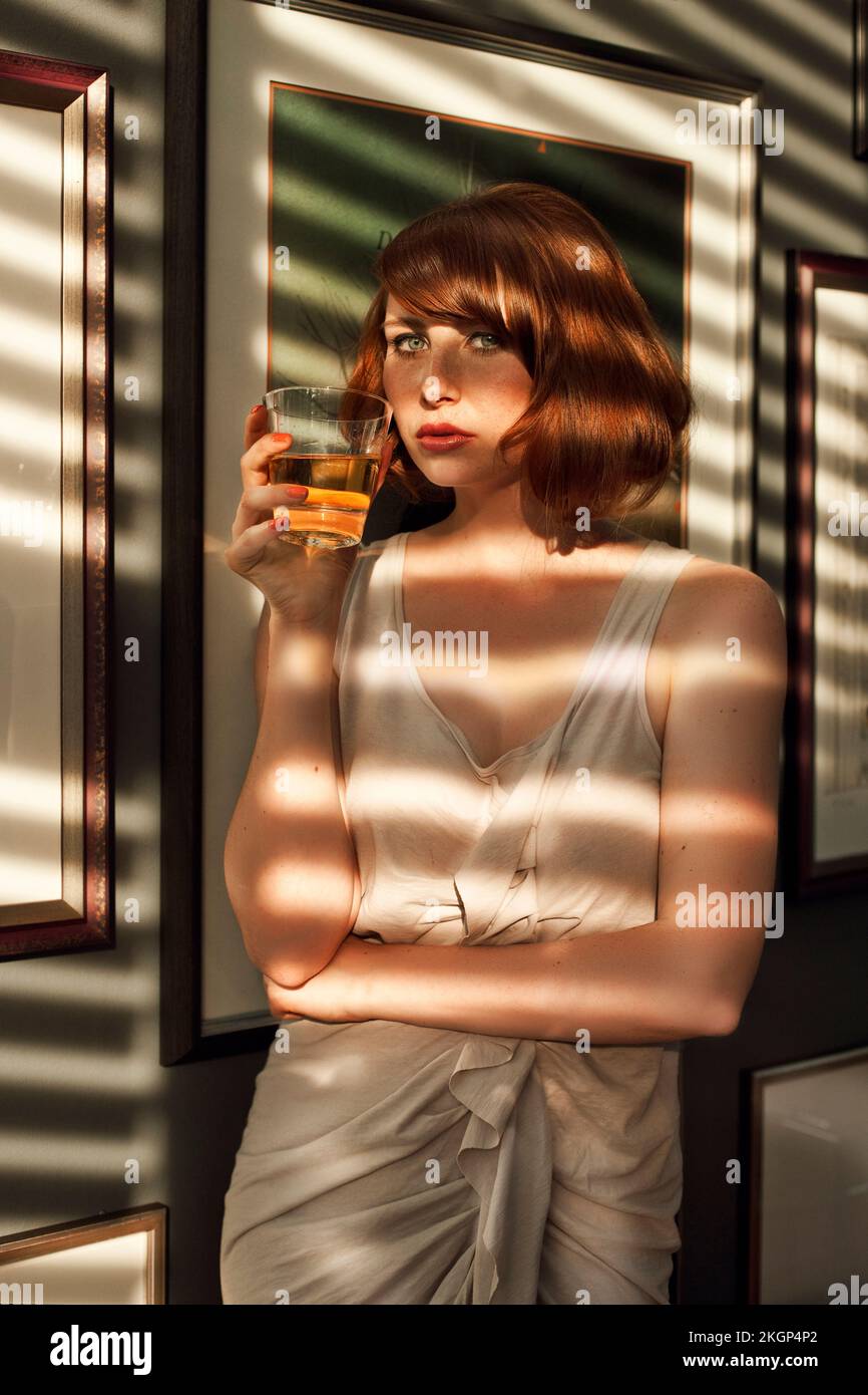 Eine Frau trinkt in einem schattigen Raum Stockfoto
