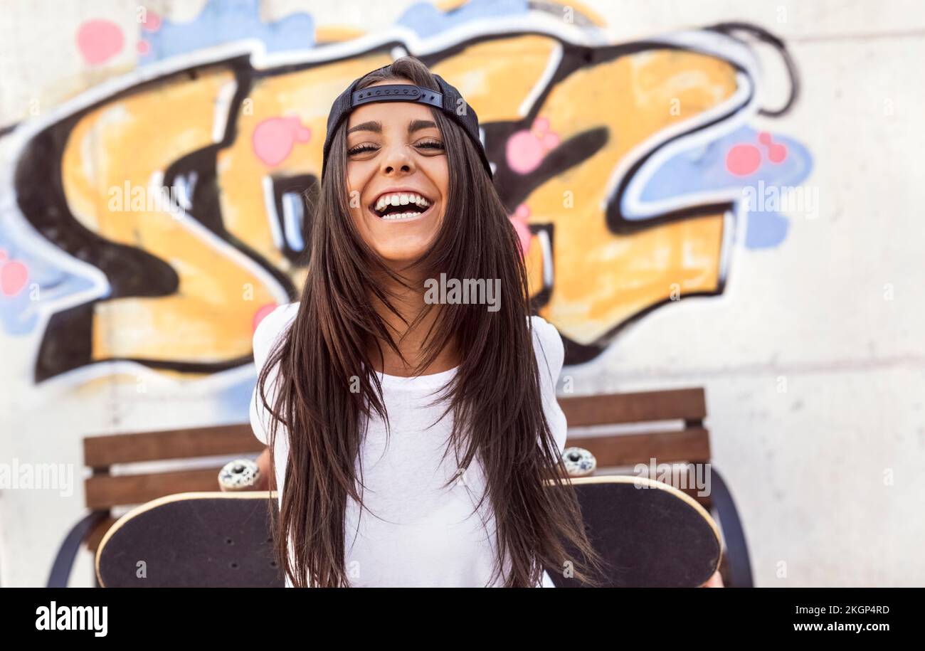 Lachende junge Frau mit Skateboard Stockfoto