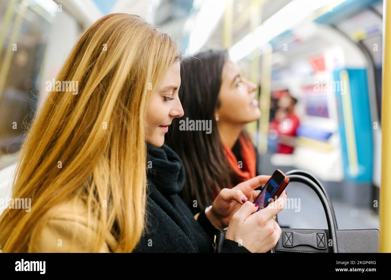 Großbritannien, London, zwei junge Frauen im Untergrund, eine mit Smartphone Stockfoto