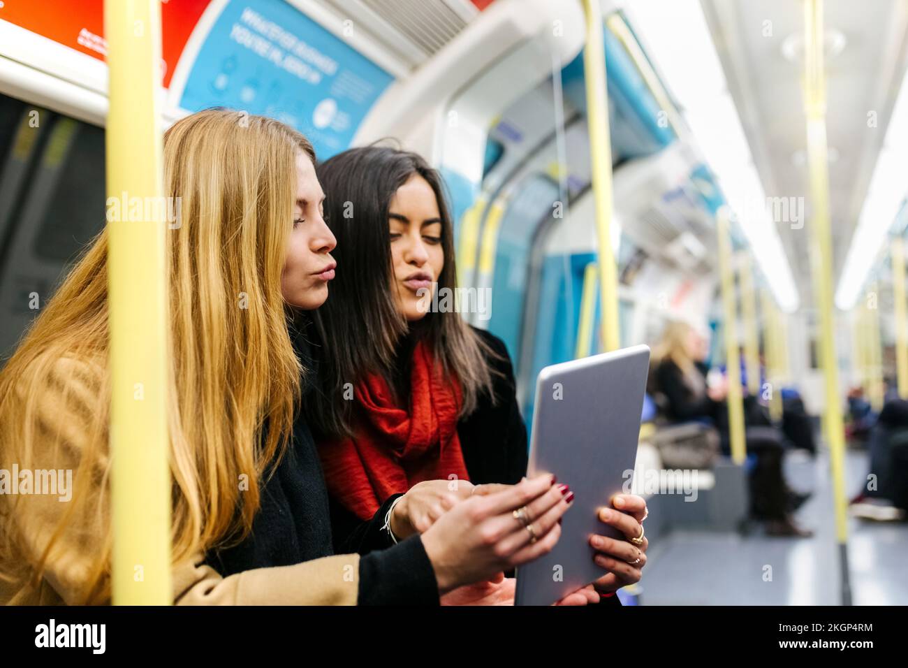 Großbritannien, London, zwei junge Frauen im Untergrund, die ein digitales Tablet benutzen Stockfoto