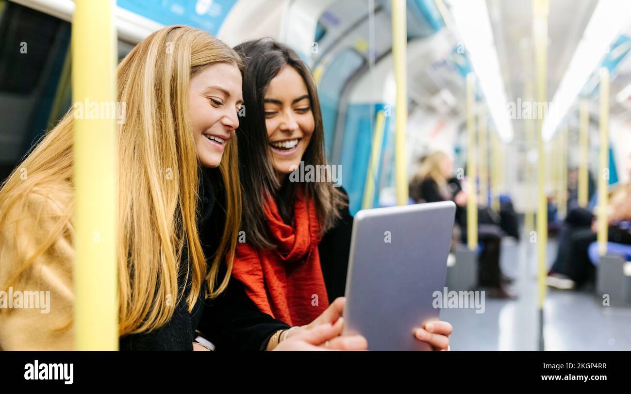 Großbritannien, London, zwei junge Frauen im Untergrund, die ein digitales Tablet benutzen Stockfoto