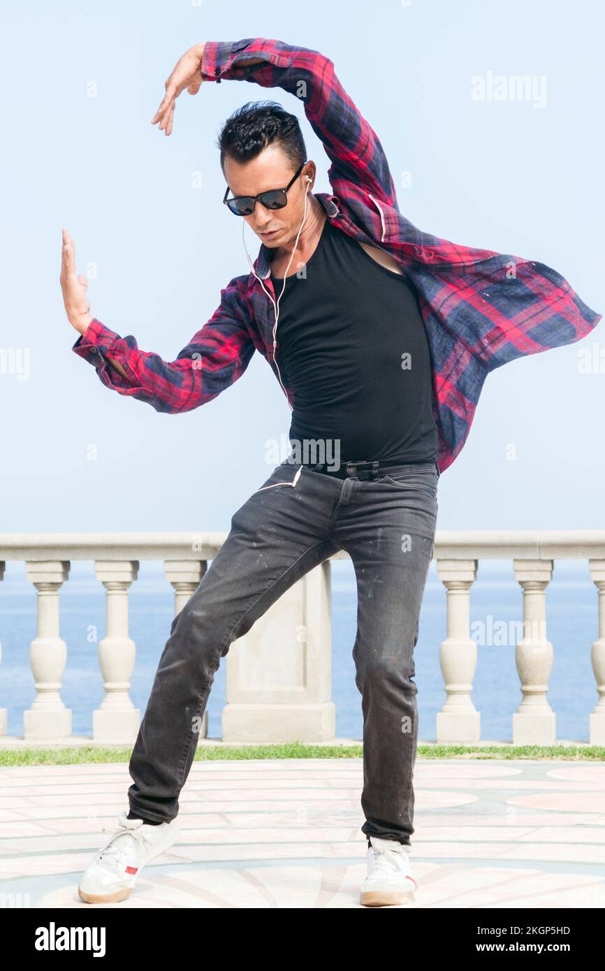 Ein Mann mit Sonnenbrille, der vor dem Geländer tanzt Stockfoto